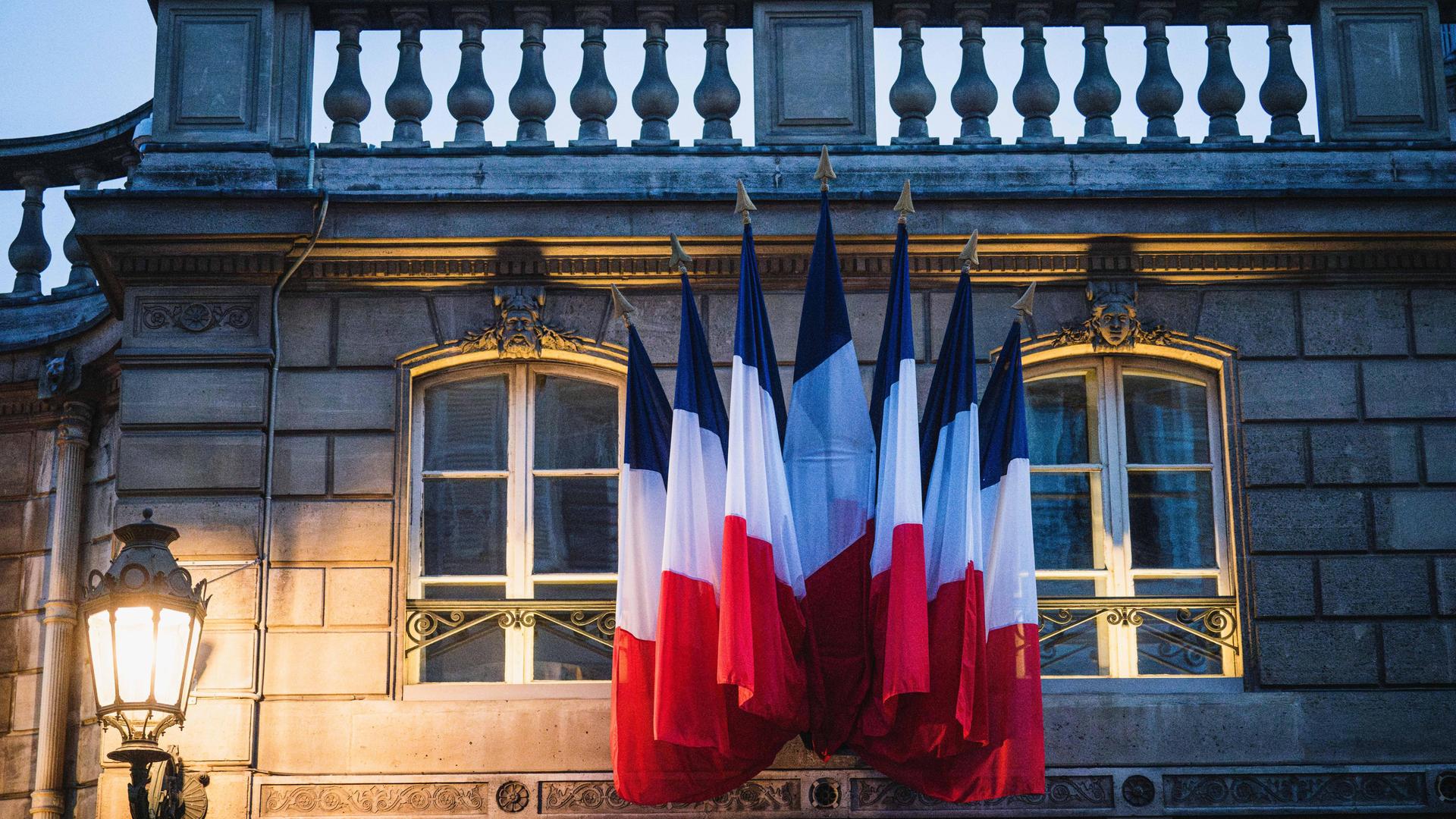 Französische Flaggen an der Fassade des Elysee-Palastes im Abendlicht.