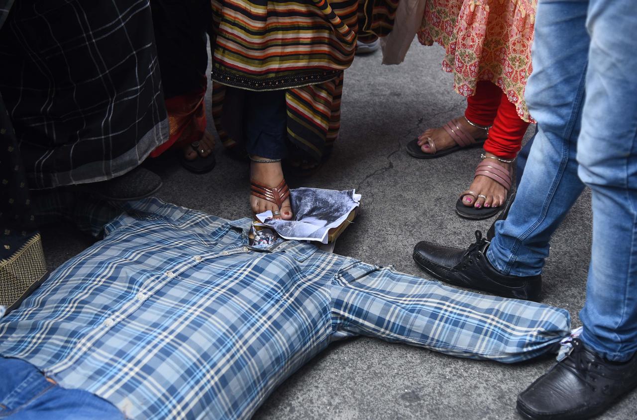 Demonstration in Mumbai. Füße in Sandalen treten auf eine am Boden liegende Puppe mit einem Foto als Kopf, die einen Mann zeigt, der in Delhi seine Freundin Shraddha Walkar brutal ermordet haben soll.