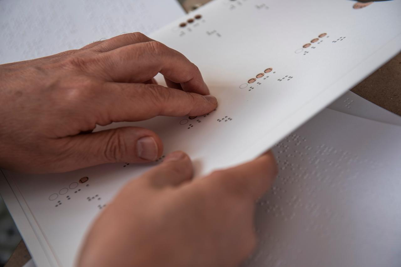 Eine Hand fährt über Erklärungen zur Wahl in Braille-Schrift