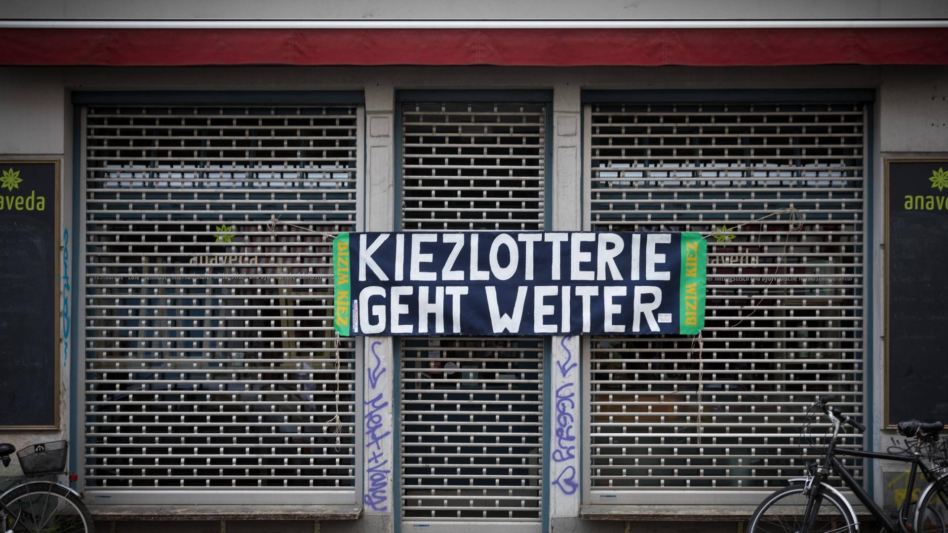 An einem geschlossenen Ladengeschäft in Berlin Kreuzberg steht ein Transparent "Kiezlotterie geht weiter" An einem geschlossenen Ladengeschäft in Berlin Kreuzberg steht ein Transparent "Kiezlotterie geht weiter"
