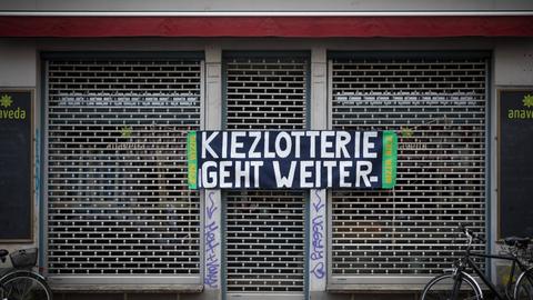 An einem geschlossenen Ladengeschäft in Berlin Kreuzberg steht ein Transparent "Kiezlotterie geht weiter"