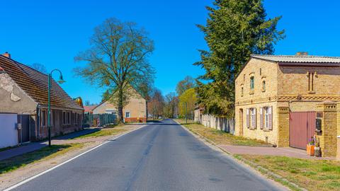 Eine Landstraße, die durch ein Dorf führt. Rechts und links sind alte Häuser.