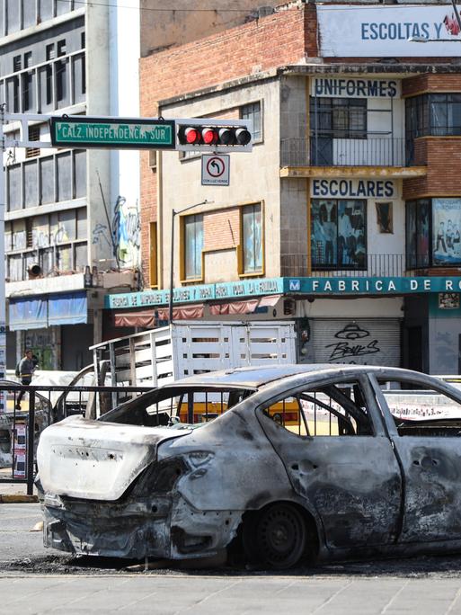 Ein ausgebranntes Auto steht auf einer Straßenkreuzung in Guadalajara.
