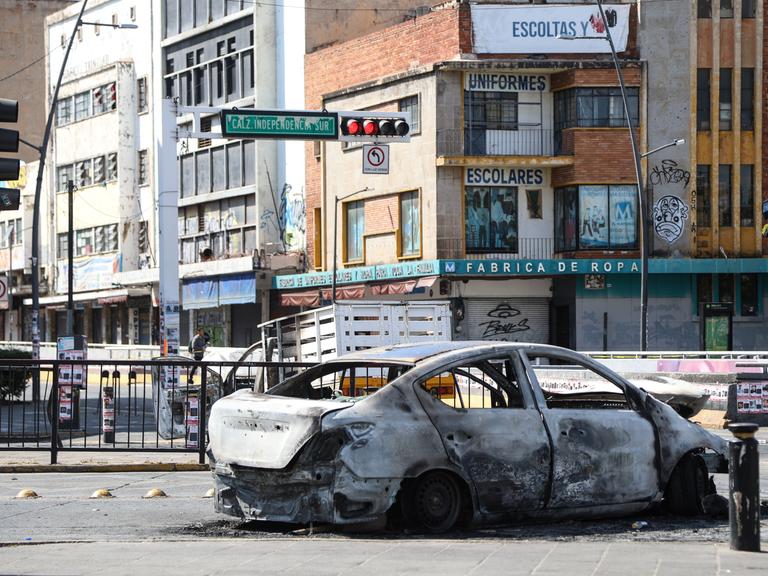 Ein ausgebranntes Auto steht auf einer Straßenkreuzung in Guadalajara.