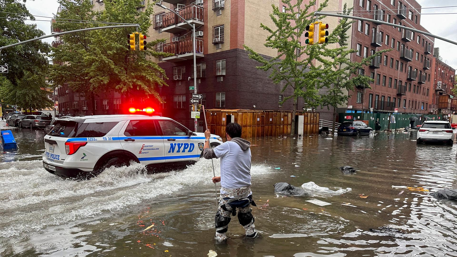 Ein Mann versucht im Stadtbezirk Brooklyn einen Abfluss im Hochwasser zu reinigen. Heftiger Regen hat in der Millionenmetropole New York zu Überschwemmungen und Sperrungen von Autobahnen, Straßen und Flughafenterminals geführt. Foto: Jake Offenhartz/AP/dpa
