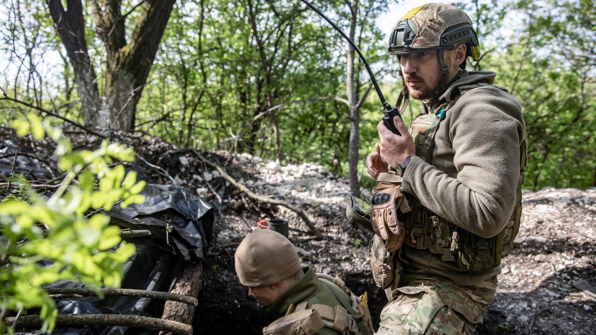 Ein ukranischer Soldat sitzt an einem Schützengraben in der Nähe der Stadt Bachmut und bedient ein Funkgerät.
