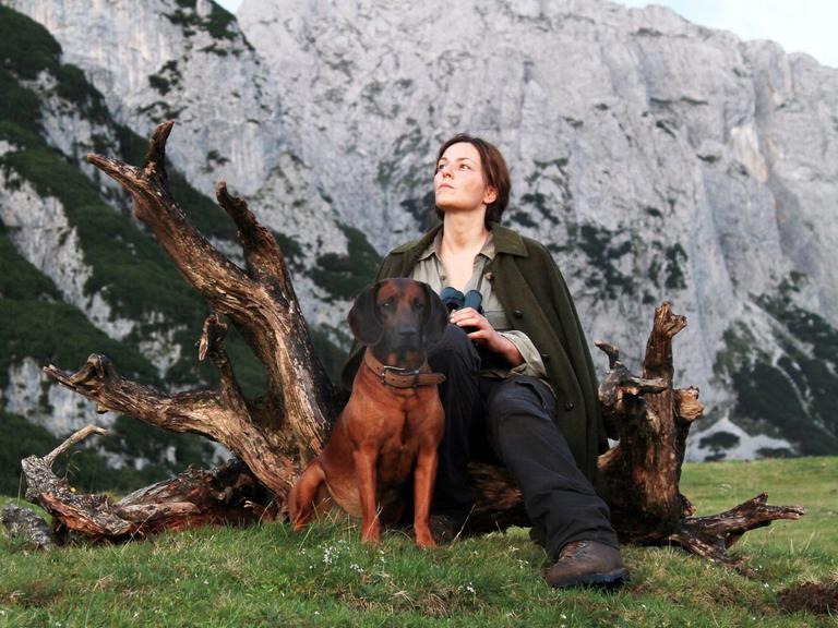 Die Schauspielerin Martina Gedeck mit einem Hund vor einer Felswand, Szene aus dem Film "Die Wand". 