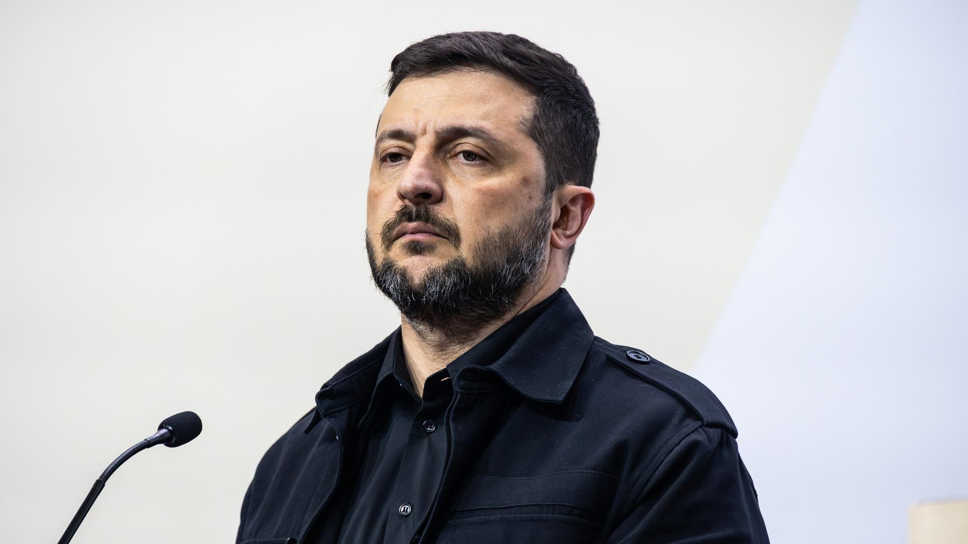 Der ukrainische Präsident Wolodymyr Selenskyj steht auf einer Pressekonferenz vor einem Mikrofon und blickt in den Raum.
