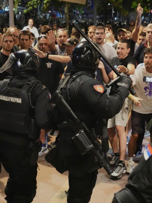 Demontranten stehen serbischen Polizisten mit Schlagstöcken gegenüber