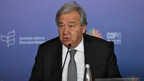 UNO-Generalsekretär Guterres sitzt bei der COP16 hinter einem Mikrofon.