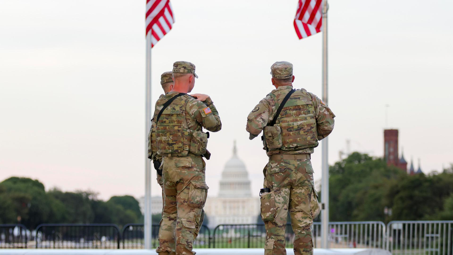 Zwei Soldaten der US National Guard stehen in Washington unter zwei US-Flaggen Zwei Soldaten der US National Guard stehen in Washington unter zwei US-Flaggen