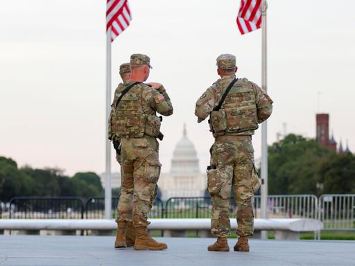 Zwei Soldaten der US National Guard stehen in Washington unter zwei US-Flaggen