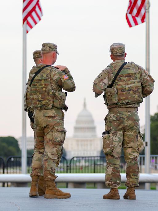 Zwei Soldaten der US National Guard stehen in Washington unter zwei US-Flaggen