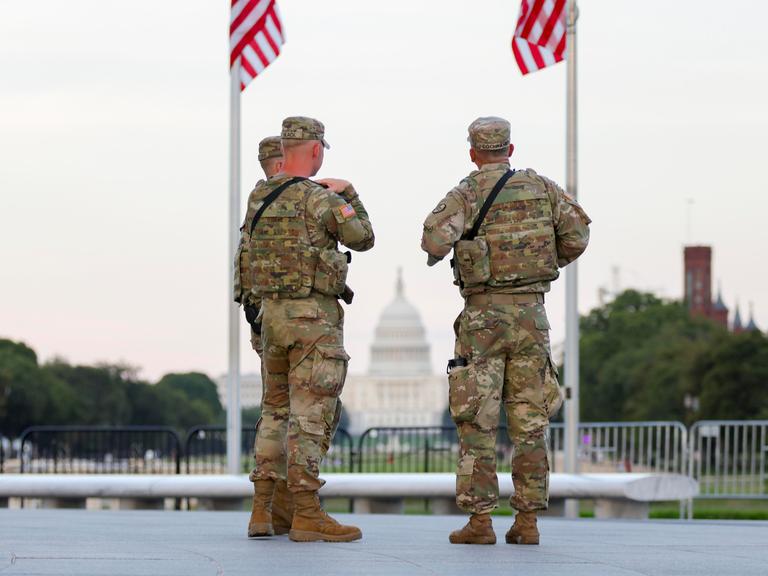 Zwei Soldaten der US National Guard stehen in Washington unter zwei US-Flaggen