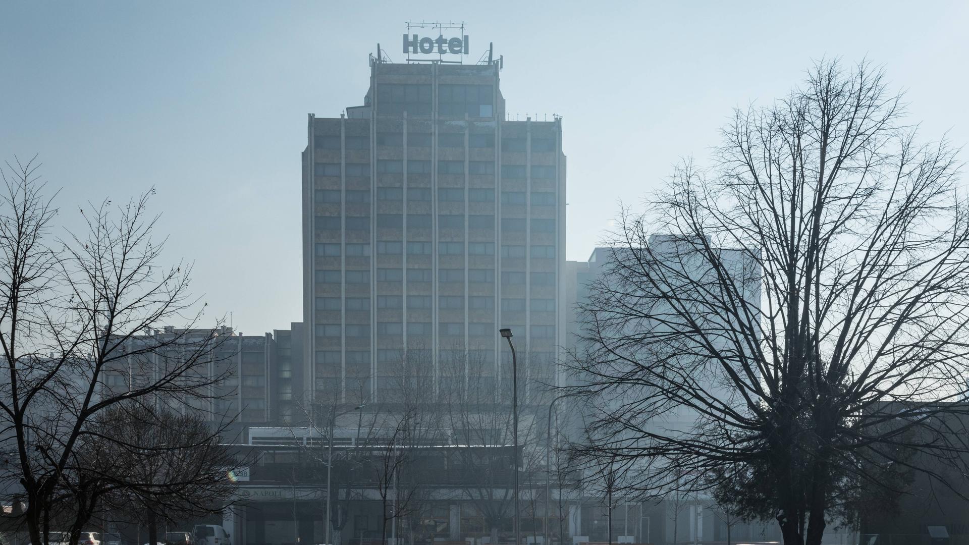 Ein tristes Hochhaus mit der Aufschrift "Hotel" auf dem Dach steht in einer verschneiten Stadt.
