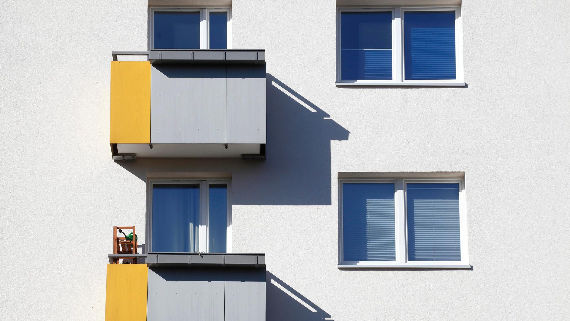 Zwei Balkone und die daneben liegenden Fenster in einem weißen Mietshaus in Bremen. 