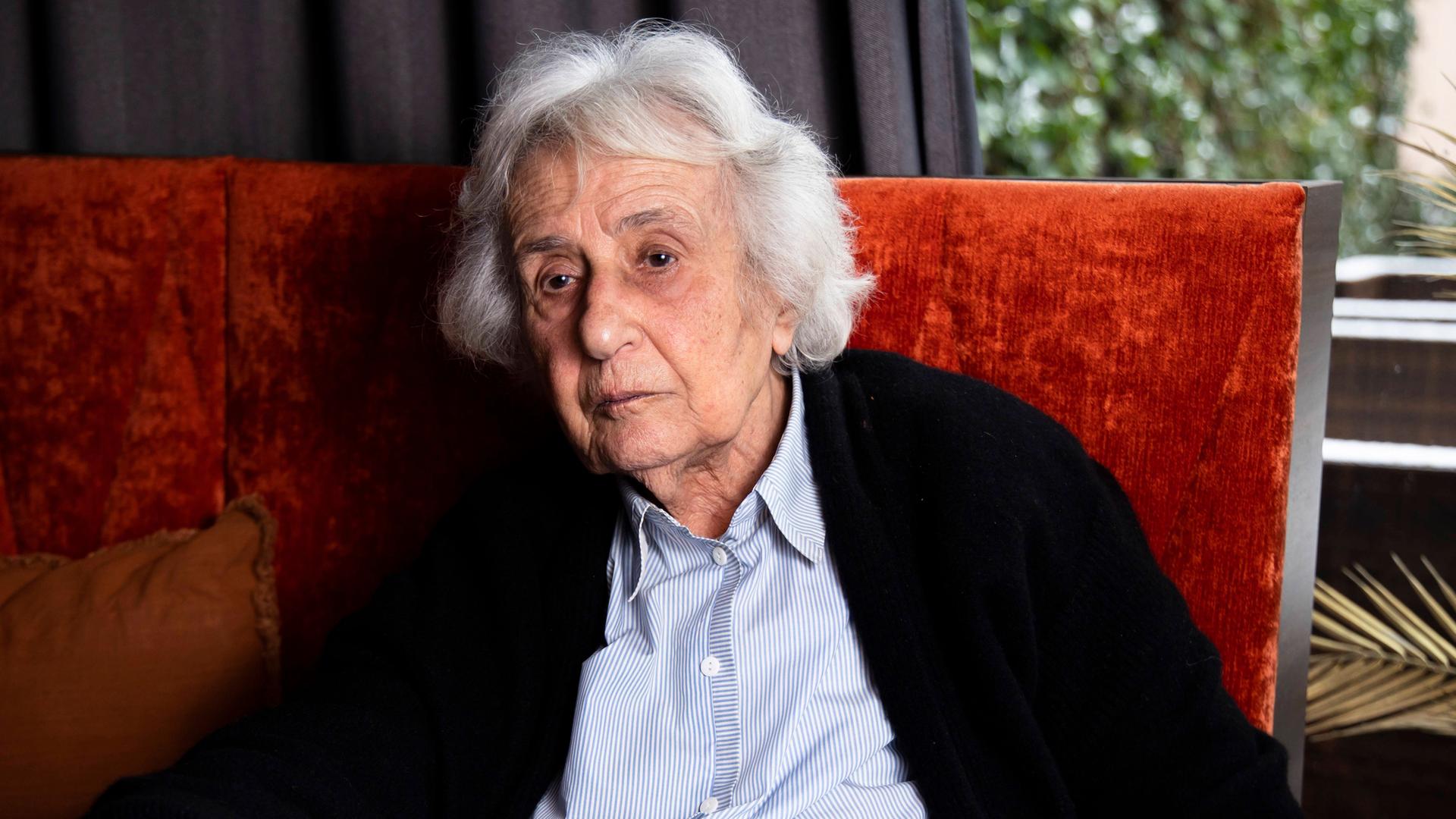 Die Holocaust-Überlebende Anita Lasker-Wallfisch sitzt am am 6. Februar 2023 auf einer roten Polsterbank an einem Tisch