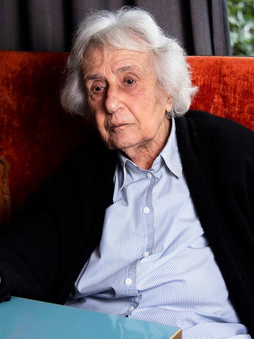 Die Holocaust-Überlebende Anita Lasker-Wallfisch sitzt am am 6. Februar 2023 auf einer roten Polsterbank an einem Tisch