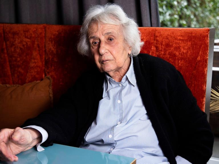 Die Holocaust-Überlebende Anita Lasker-Wallfisch sitzt am am 6. Februar 2023 auf einer roten Polsterbank an einem Tisch