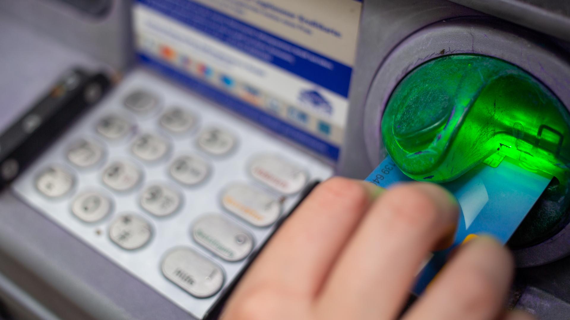 Eine Bankkundin steckt ihre Girokarte in einen Geldautomaten.