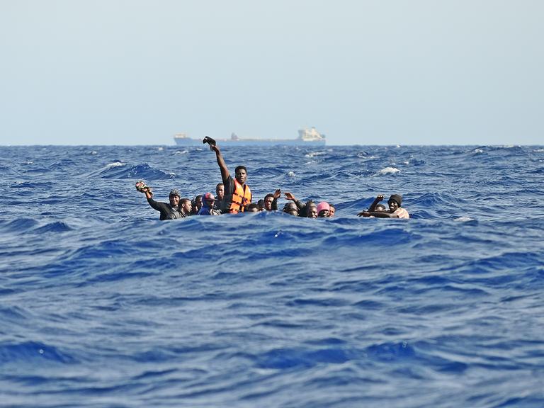 Migration über das Mittelmeer: Ein Holzboot mit etwa 30 Menschen an Bord ist bei hohen Wellengang in Seenot geraten. Die Männer rufen um Hilfe.