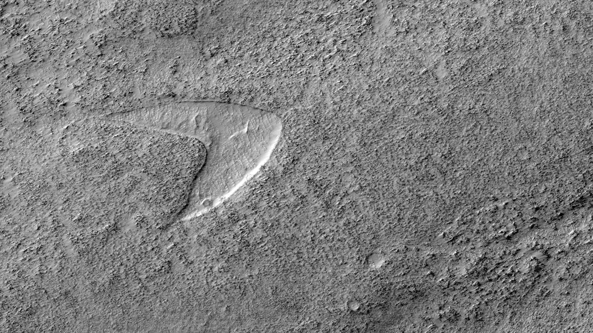 Ein Schwarz-Weiß-Foto zeigt eine Oberflächen-Formation auf dem Mars, das dem Star.Trek-Logo ähnelt.
