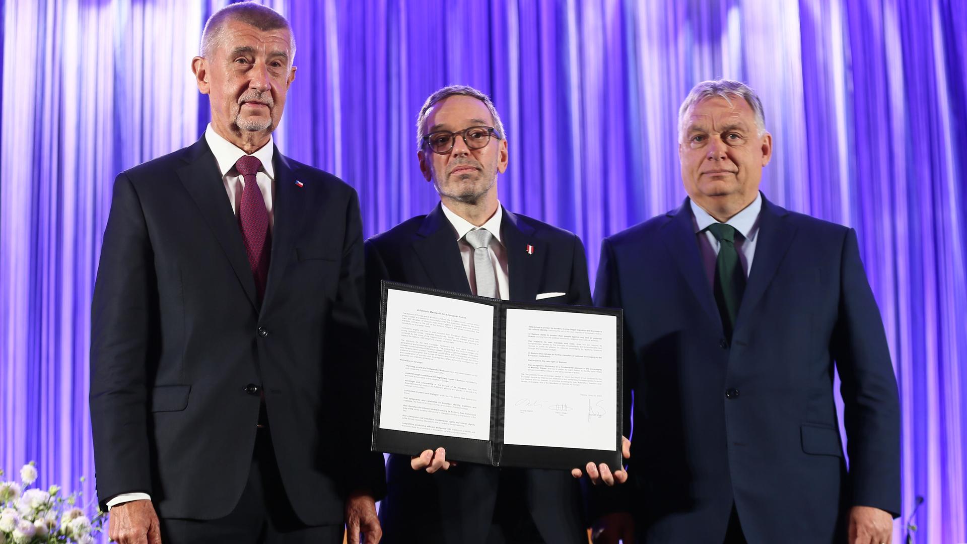 Andrej Babis, Herbert Kickl und Viktor Orbán stehen auf einer Bühne und präsentieren einen unterschriebenen Vertrag.