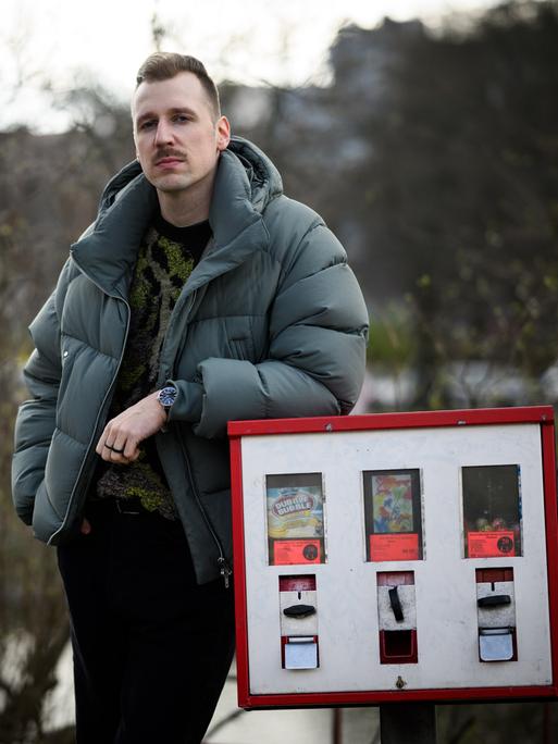 Lukas Strobel, besser bekannt als der Rapper Alligatoah, steht neben einem Kaugummiautomat.