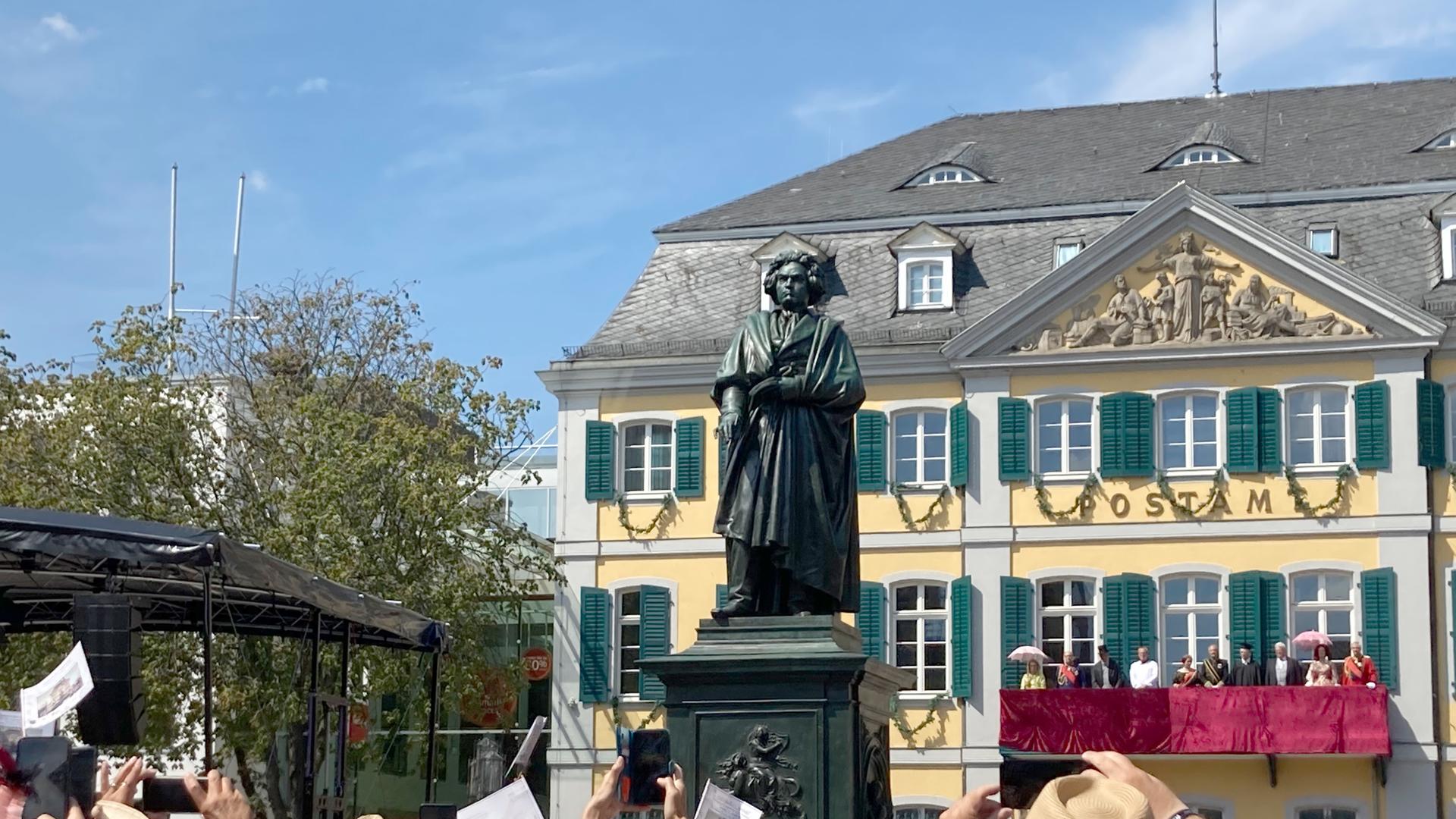Menschen fotografieren ein Denkmal mit der Statue des Komponisten Ludwig van Beethoven.