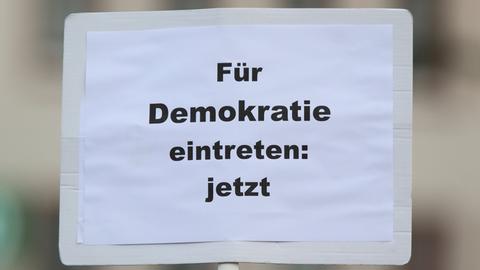 Plakat mit der Aufschrift "Für Demokratie eintreten: jetzt" bei der bundesweite Gedenkdemonstration vier Jahre nach dem rassistischen Anschlag vom 19. Februar 2020 in Hanau.