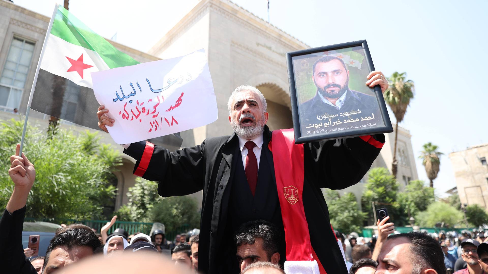 Demonstration vor dem Justizgebäude in Damaskus. Ein älterer Mann hält das Bild eines Angehörigen hoch, der zum Opfer des Assad-Regimes wurde. 