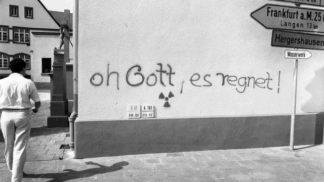 "Oh Gott, es regnet!", darunter ein Radioaktivitäts-Warnzeichen, hat jemand auf eine Häuserwand in Eppertshausen, in der Nähe von Frankfurt/Main geschrieben. Bild vom 5. Mai 1986.