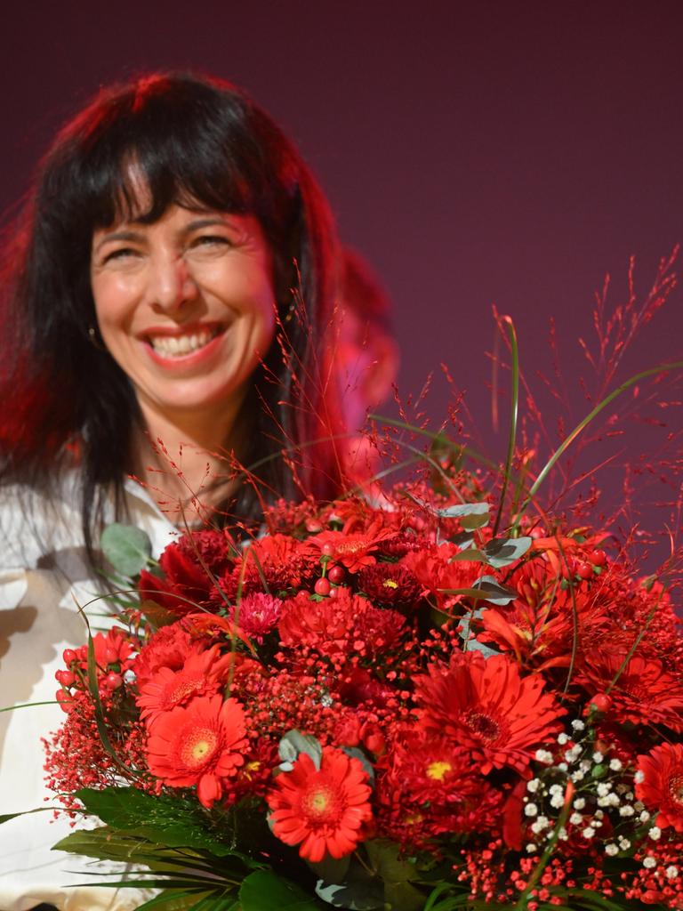 Elif Eralp steht mit einem Blumenstrauß auf der Bühne und lächelt in die Kamera. Elif Eralp steht mit einem Blumenstrauß auf der Bühne und lächelt in die Kamera.