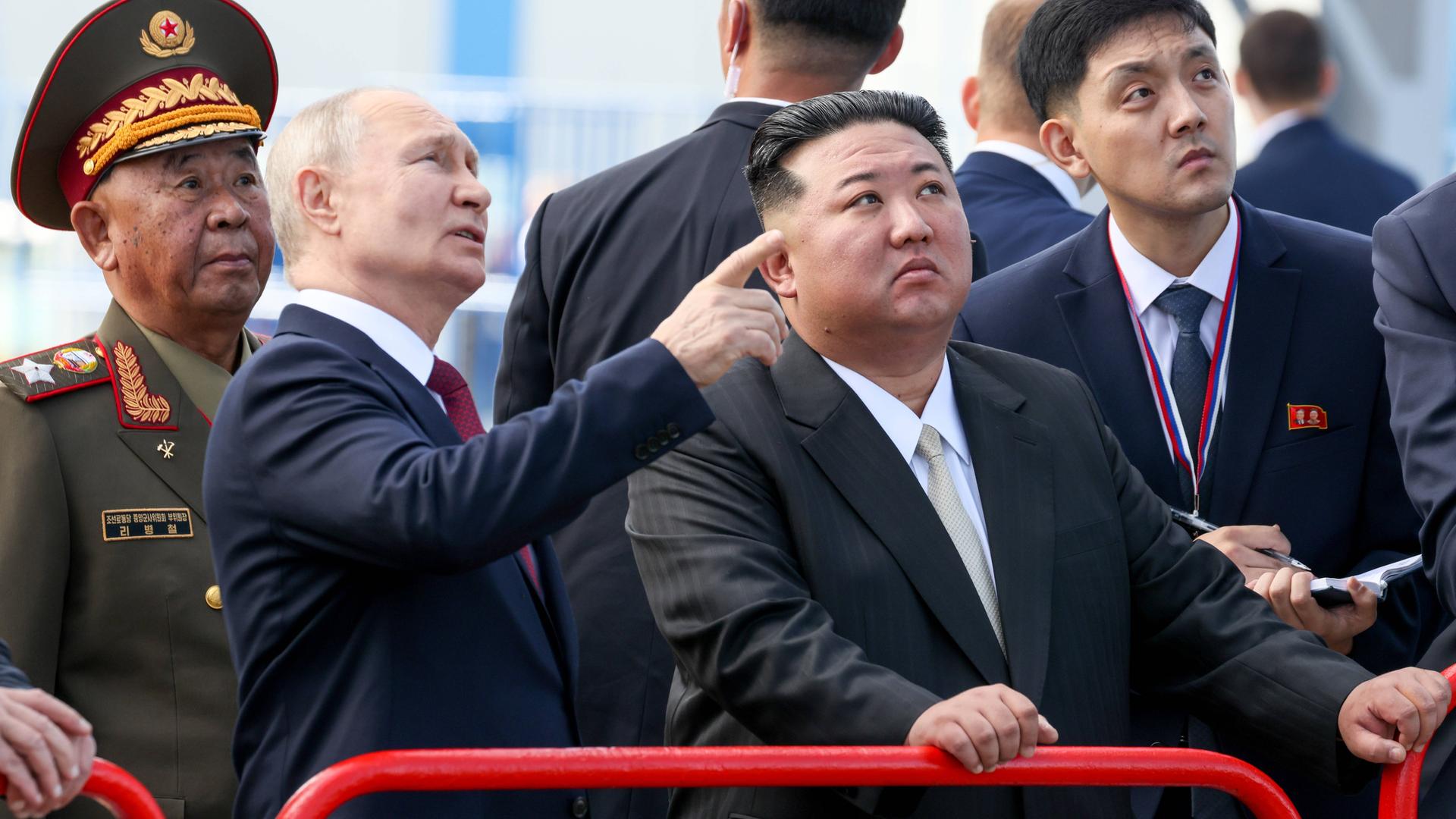 Wladimir Putin und Kim Jong Un stehen nebeneinander und gucken nach oben.