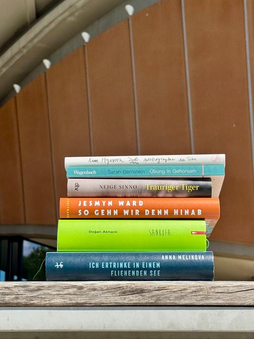 Das Bild zeigt einen Bücherstapel mit den Werken, die auf der Shortlist des Deutschen Literaturpreises 2025 stehen