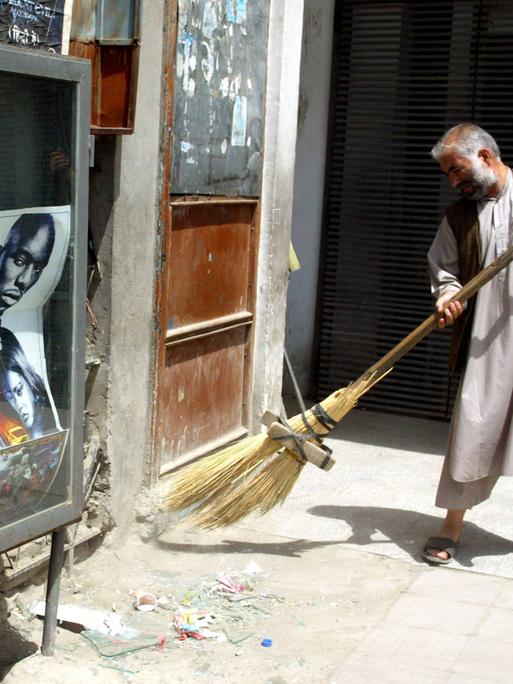 Ein Mann fegt nach einem Bombenanschlag in Kabul Glasscherben von einem zersprungener Fenster zusammen, 2006.