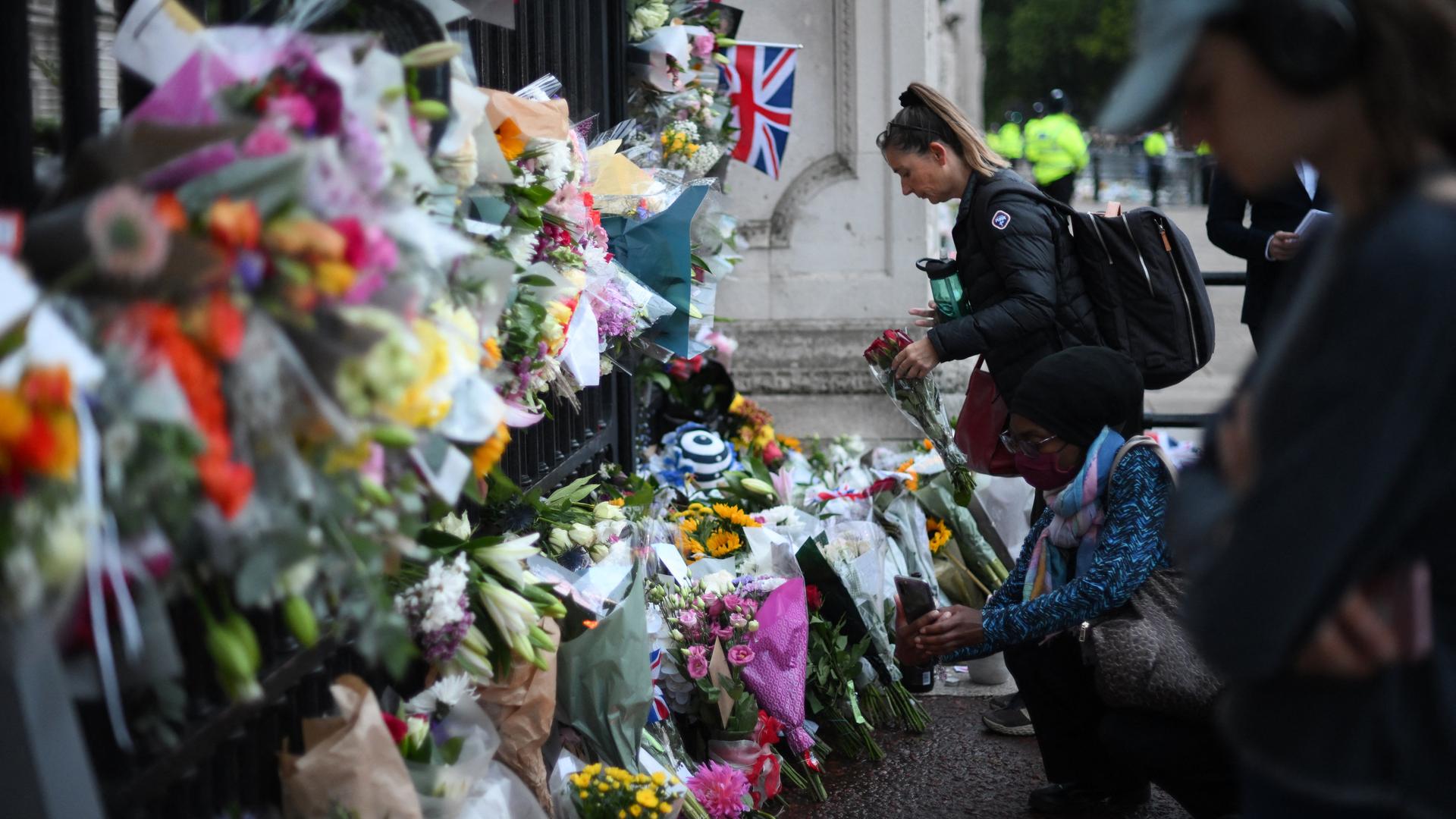 Am Buckingham Palace in London haben zahlreiche Menschen als Zeichen ihrer Trauer um Queen Elizabeth II. Blumen niedergelegt. Eine Frau kniet davor.