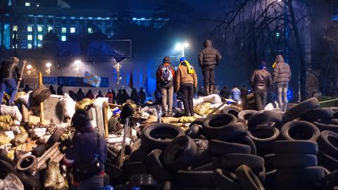 Majdan-Proteste in Kiew im Dezember 2013. Demonstrierende Menschen stehen auf einem Berg von Autoreifen.  