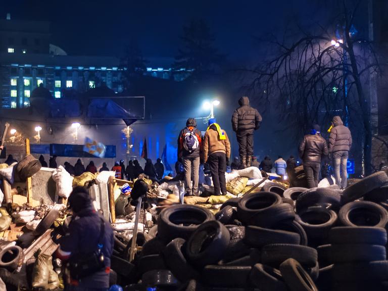 Majdan-Proteste in Kiew im Dezember 2013. Demonstrierende Menschen stehen auf einem Berg von Autoreifen.  