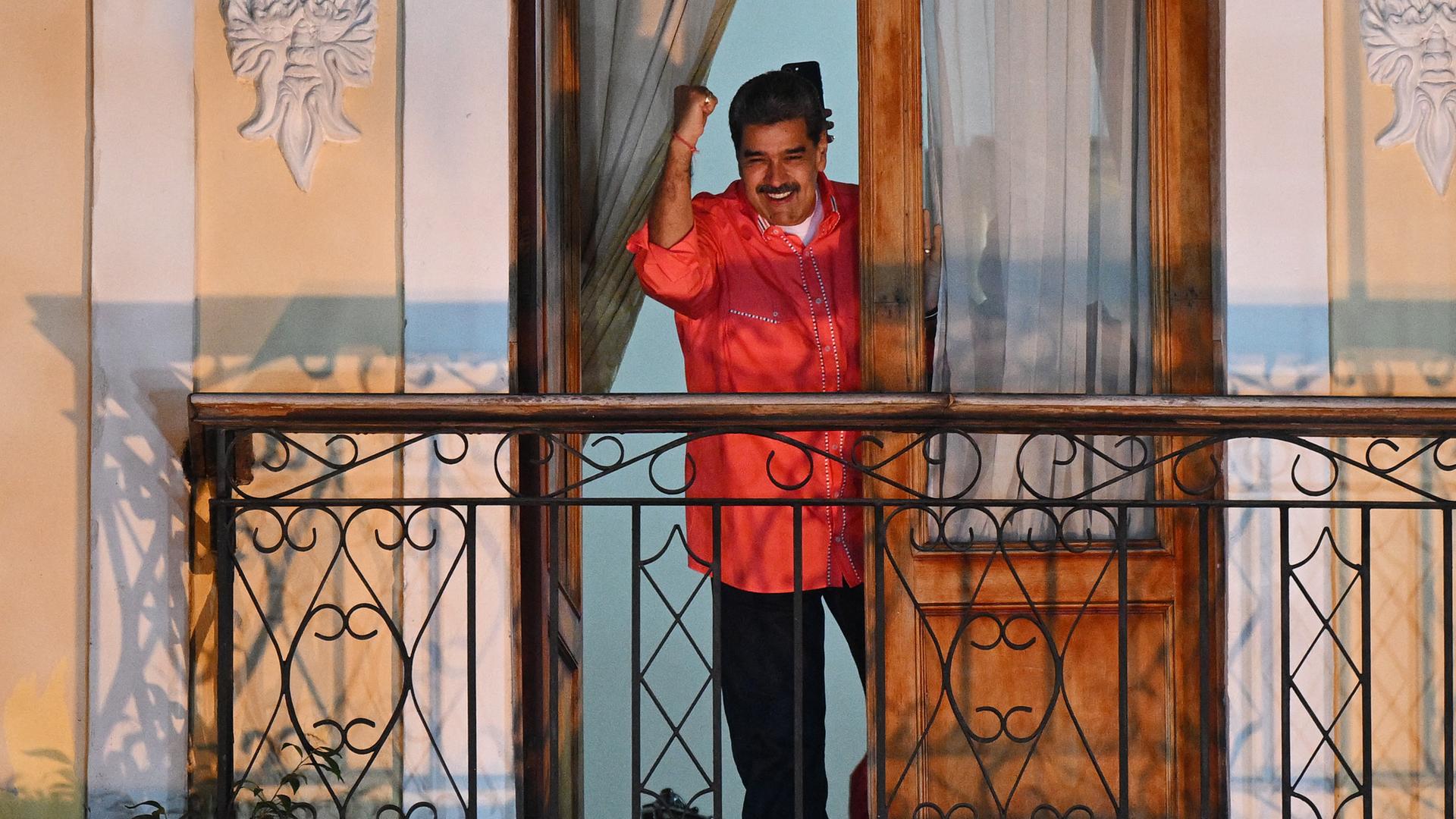 Venezuelas Präsident Maduro steht nach dem Sieg bei der Parlamentswahl auf einem Balkon und freut sich. Venezuelas Präsident Maduro steht nach dem Sieg bei der Parlamentswahl auf einem Balkon und freut sich.