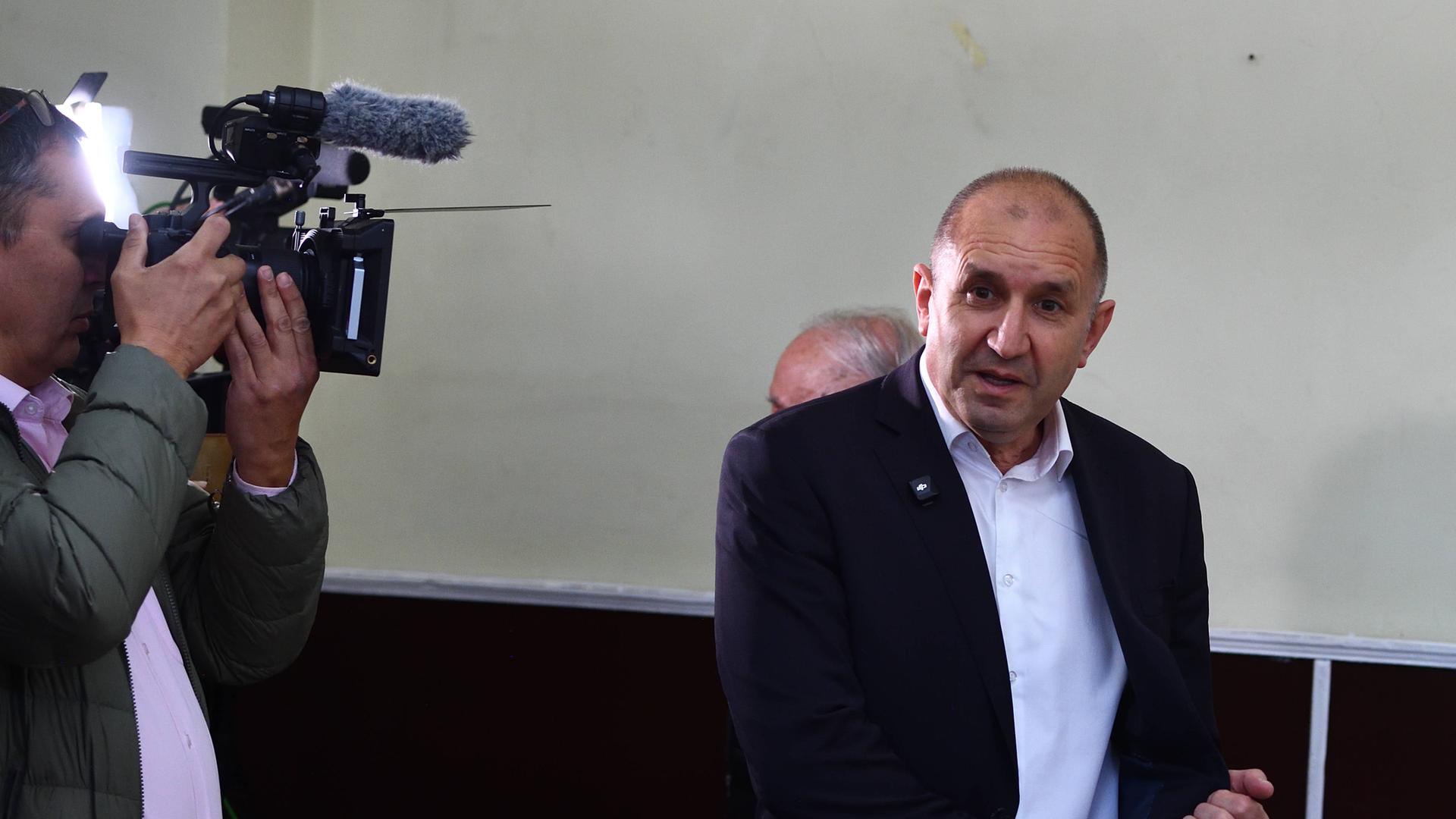 Der ehemalige Präsident Rumen Radev wird bei der Wahl fotografiert. Er hat eine Halbglatze und kurze Haare. Er trägt einen dunklen Anzug mit offenem Jackett und ein weißes Hemd.