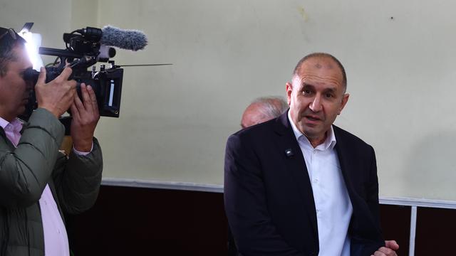 Der ehemalige Präsident Rumen Radev wird bei der Wahl fotografiert. Er hat eine Halbglatze und kurze Haare. Er trägt einen dunklen Anzug mit offenem Jackett und ein weißes Hemd.