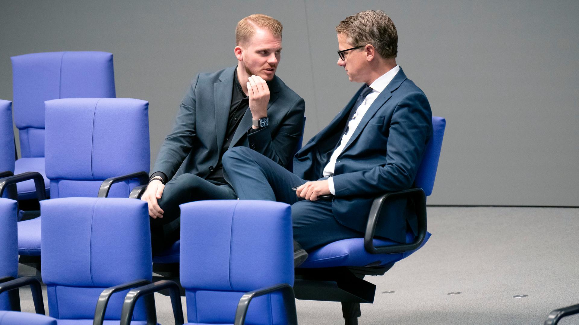 Tim Klüssendorf und Carsten Linnemann sitzen im Plenarsaal zusammen und unterhalten sich Tim Klüssendorf und Carsten Linnemann sitzen im Plenarsaal zusammen und unterhalten sich