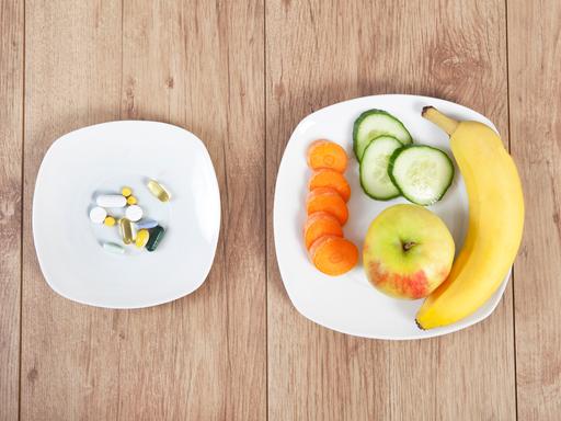 Zwei Teller: auf einem Tabletten, auf dem anderen Obst und Gemüse.