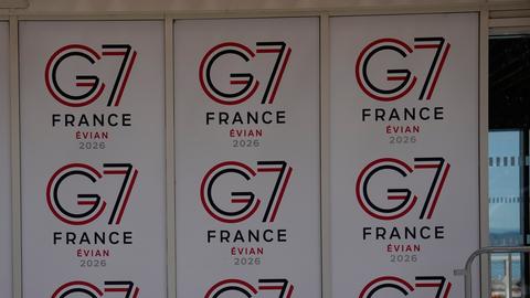 Eine Wand, auf der mehrmals das Logo des G7-Treffens zu sehen ist. In kleiner werdender Schrift steht untereinander G7, France, Evian und 2026.