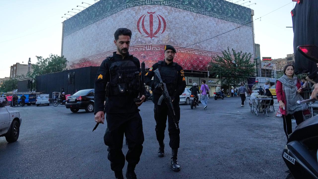 Polizisten gehen in Teheran auf dem Platz der Islamischen Revolution vor einem riesigen Banner mit der iranischen Flagge vorbei. Polizisten gehen in Teheran auf dem Platz der Islamischen Revolution vor einem riesigen Banner mit der iranischen Flagge vorbei.