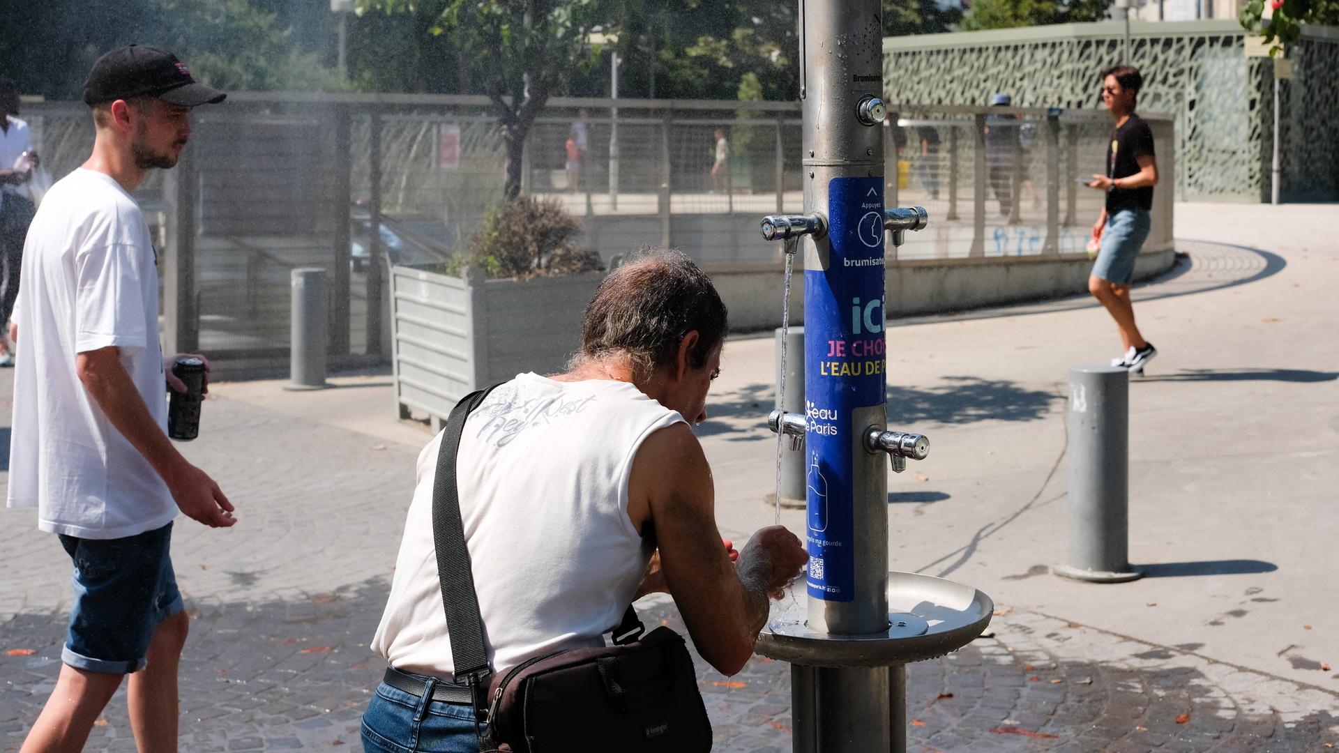 Menschen an einem Wasserspender im sommerlichen und von Hitze geplagten Paris. 