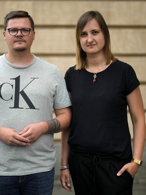 Ein junger Mann in hellgrauem T-Shirt und eine junge Frauen in einem dunklen T-Shirt stehen nebeneinander. Es sind die für ihre Zivilcourage ausgezeichneten Lehrer Max Teske und Laura Nickel.