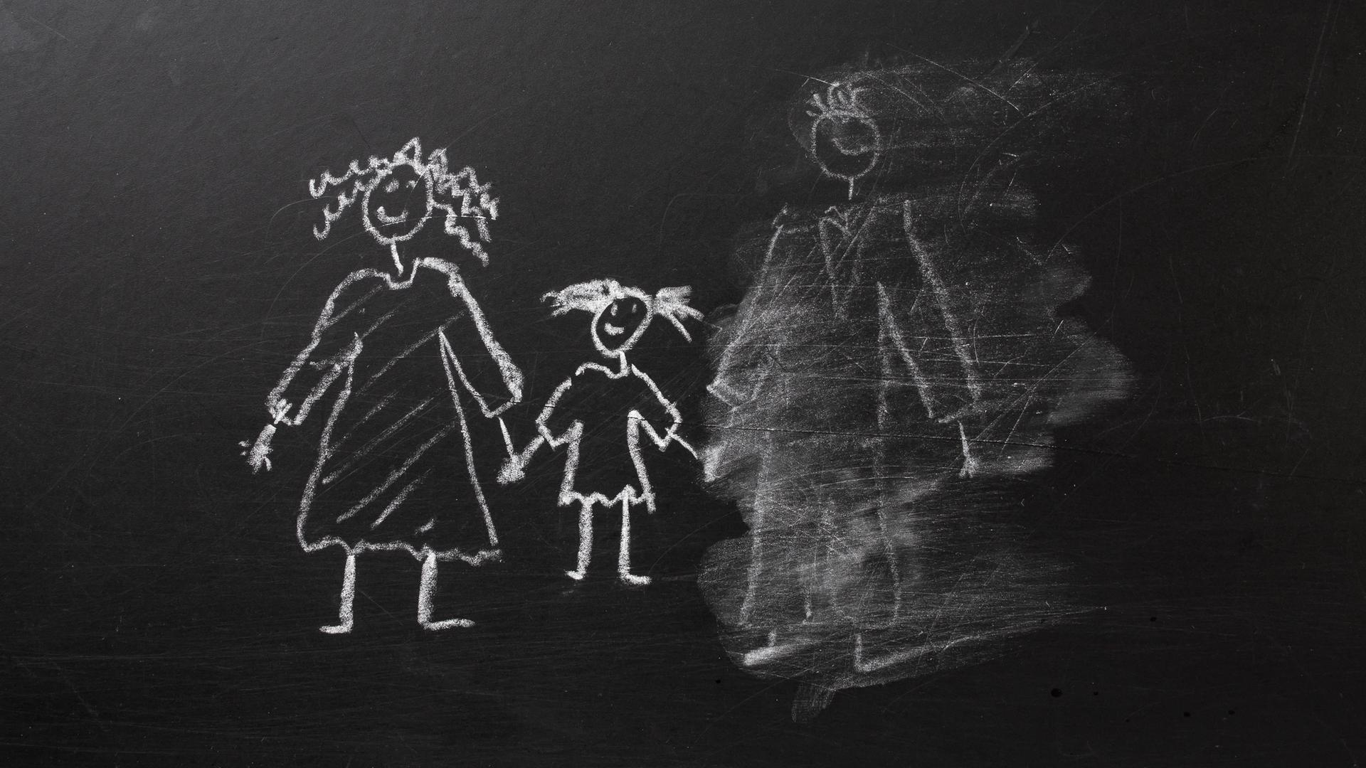 Kreidezeichnung einer Familie an einer Tafel, bei der der Vater halb weggewischt wurde.