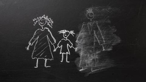 Kreidezeichnung einer Familie an einer Tafel, bei der der Vater halb weggewischt wurde.